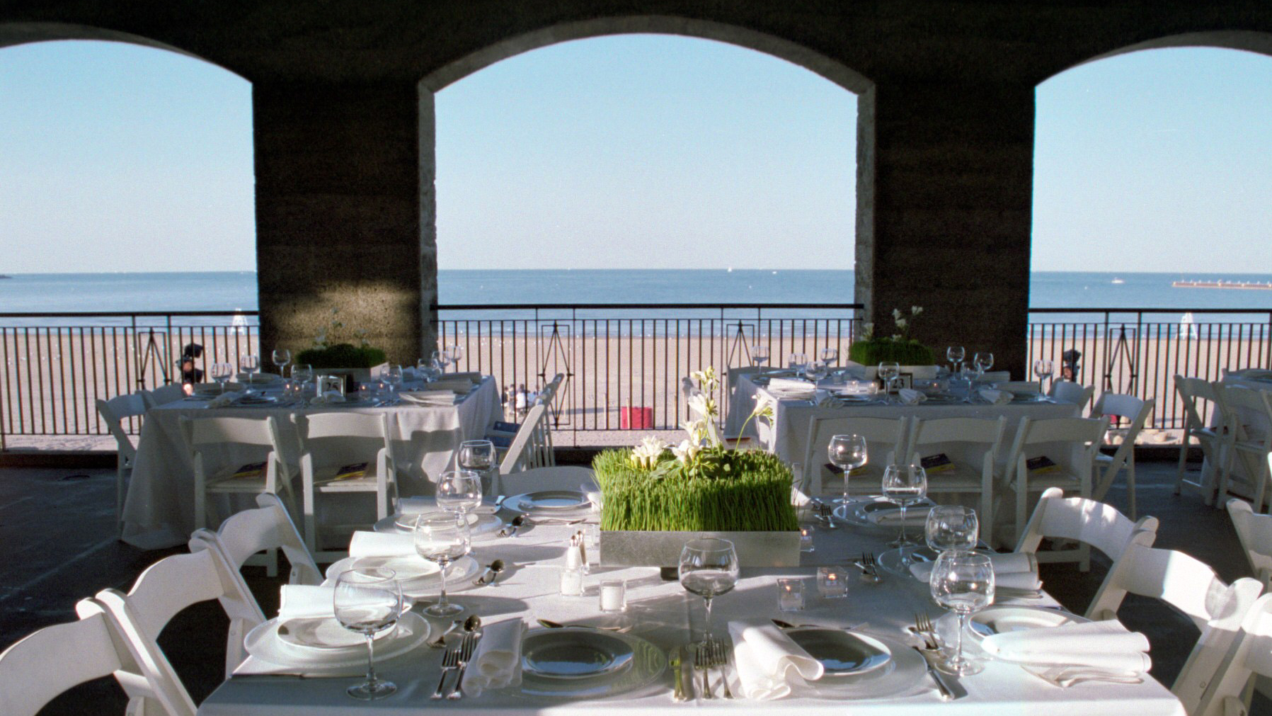 Elegant beachside reception with white tablecloths, place settings, and ocean view.